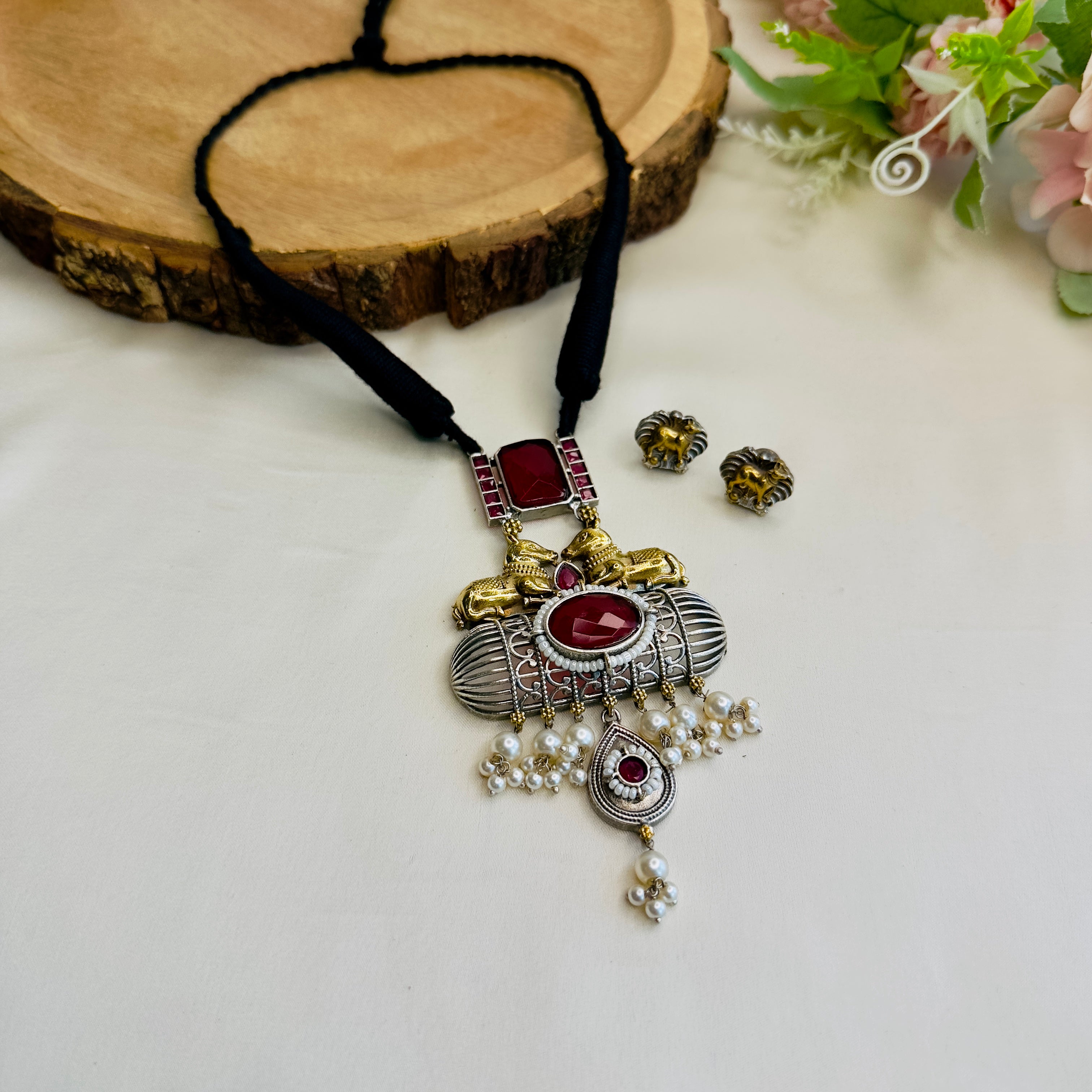 Ornate necklace with red stones and gold accents on a white surface